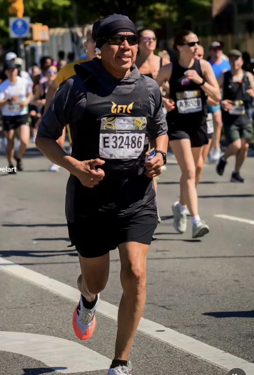 Andre Kowlessar running the Brooklyn Half Marathon in a Goldfinger Track Club singlet
